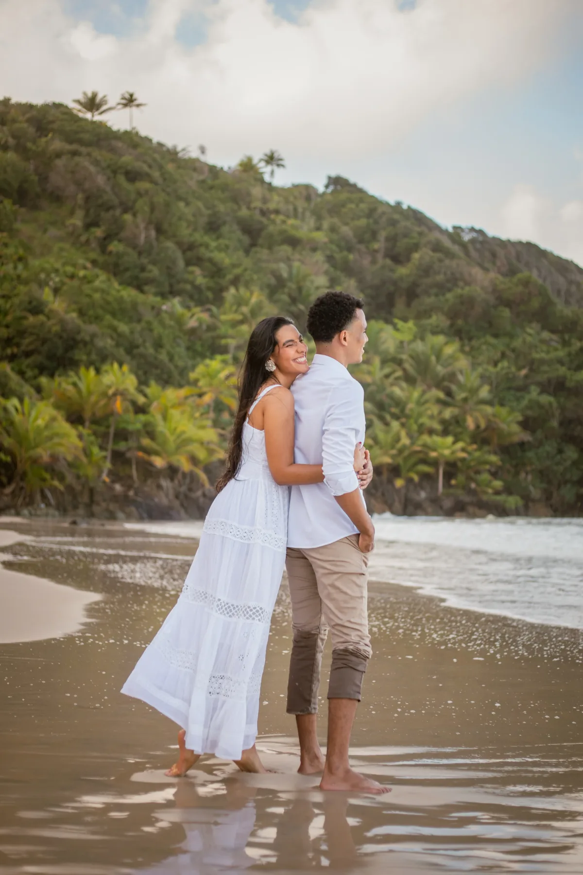 O casal abraçado na beira do mar, olhando para o horizonte