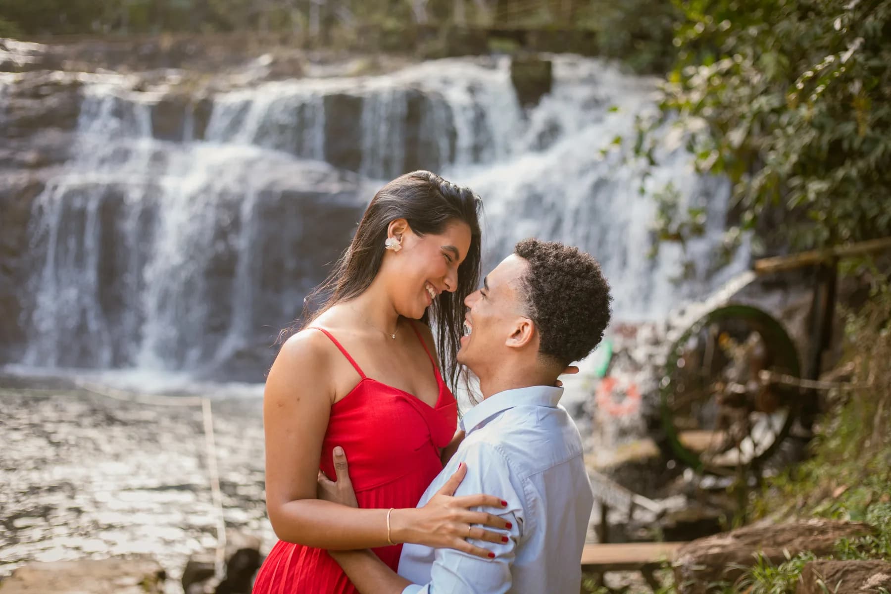 O casal rindo frente a frente, com a cachoeira ao fundo